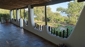 A covered outdoor area with a tiled floor, white walls, and a wooden ceiling. - Villa - Eden Rock - Santa Margherita di Pula - House with garden (Domus de Maria)