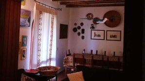 An interior with a wooden ceiling, a dining table with chairs, and a wall with framed pictures. - Villa - Eden Rock - Santa Margherita di Pula - House with garden (Domus de Maria)