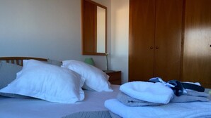 Ein Schlafzimmer mit Bett, Kissen, einem Nachttisch mit Lampe und einem Kleiderschrank.