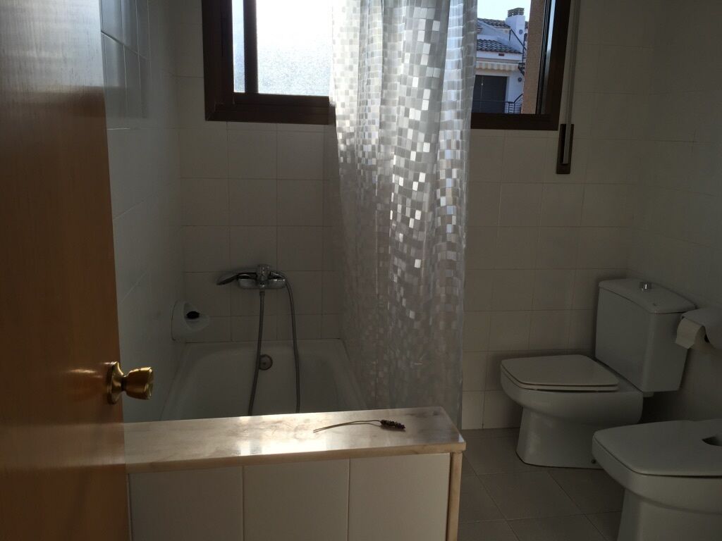 Een badkamer met een bad, toilet en douchegordijn.