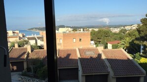 Ein Wohngebiet mit terrakottafarbenen Dächern, freiem Blick auf das Meer und einer fernen Küstenlinie.