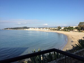 A coastal view with a sandy beach, clear blue water, and a distant town. - Altafulla Beach House in Costa Dorada, Tarragona for 8 people Air Conditioning (Altafulla)