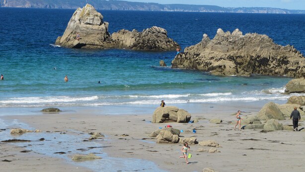 Ein Strand mit Felsformationen und ruhigem Wasser.