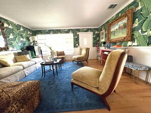 Un salon avec une moquette bleue, un canapé, un fauteuil et une bibliothèque.