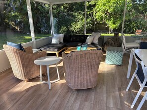 Een terras buiten met rieten meubels, een bank en een tafel.