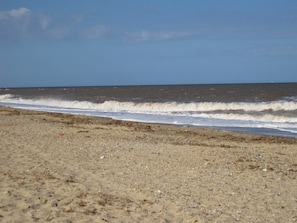 A beach with waves approaching the shore. - Henry's Cottage - a place to make you smile (Winterton on sea)
