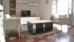Een woonkamer met een bank, een salontafel, een televisie en een boekenkast.