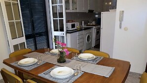 A dining table set for four with placemats, plates, and a vase with flowers. - Panoramic view over the city and the sea (Funchal)