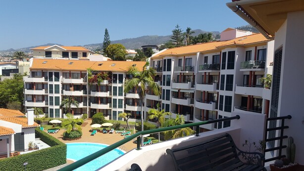 Ett hotell med flera våningar, balkonger, en swimmingpool och utsikt över det omgivande landskapet.