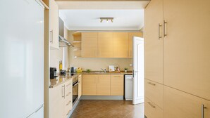 Een moderne keuken met lichte houten kastjes, een roestvrijstalen afzuigkap en een betegelde spatwand.