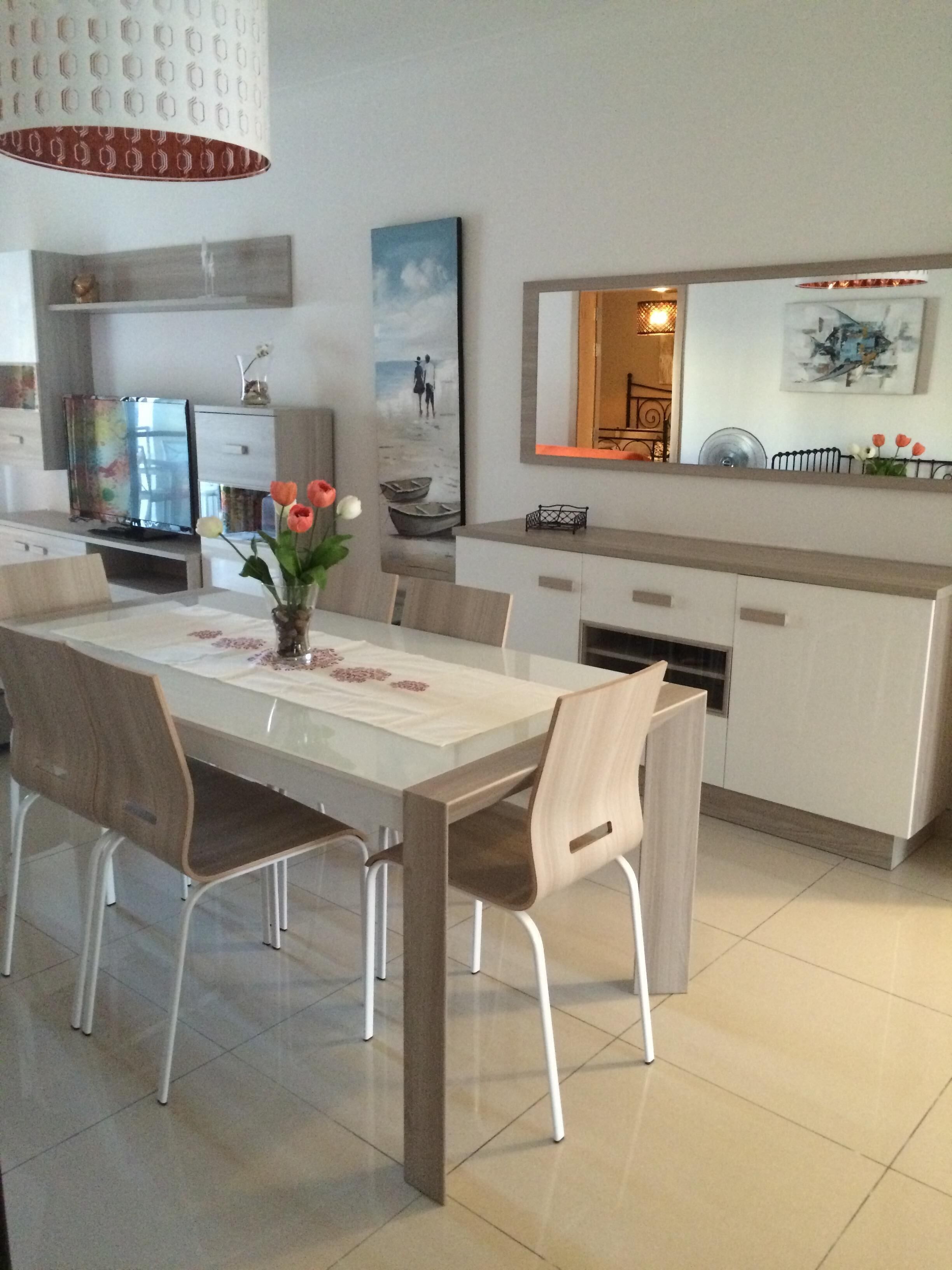 Un comedor moderno con una mesa grande, sillas y un jarrón con flores.