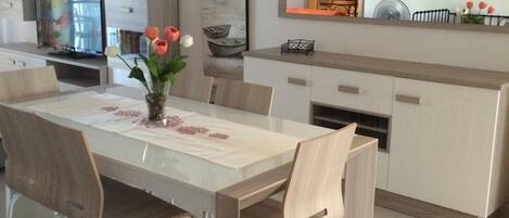 Un comedor moderno con una mesa grande, sillas y un jarrón con flores.
