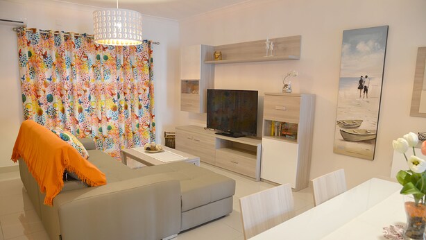 Un salon moderne avec un canapé, un téléviseur et un coin repas.