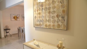 Un couloir comprenant un coin repas, une table avec une bougie et des œuvres d’art abstraites accrochées au mur.