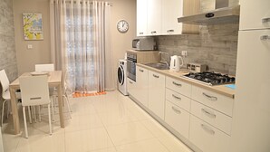 Une cuisine moderne avec un coin repas, comprenant un évier, une cuisinière, un four à micro-ondes et une horloge murale.