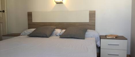 A neatly made bed with a striped bedspread, two pillows, and a nightstand with a book on it.