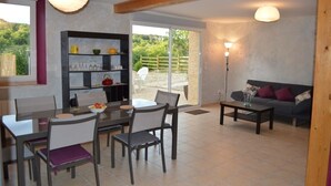 A dining area with a table and chairs, a bookshelf, a sofa, and a lamp. - Gîte des Patiasses, very spacious,between Rennes le Château and Rennes les Bains (Couiza)