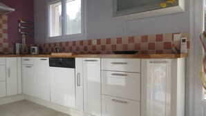 Una cocina con armarios blancos, lavavajillas y una ventana sobre el fregadero.