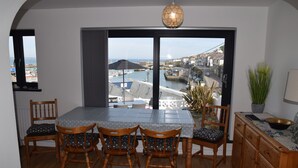 Un coin repas avec une table et des chaises, une vue sur un port et un luminaire suspendu.