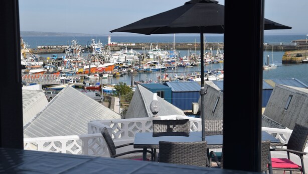 Une vue d’une marina avec des bateaux et un phare en arrière-plan.