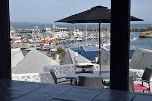 A view of a marina with boats and a lighthouse in the background. - Port View, Newlyn house with stunning views over the picturesque working port. (Penzance)