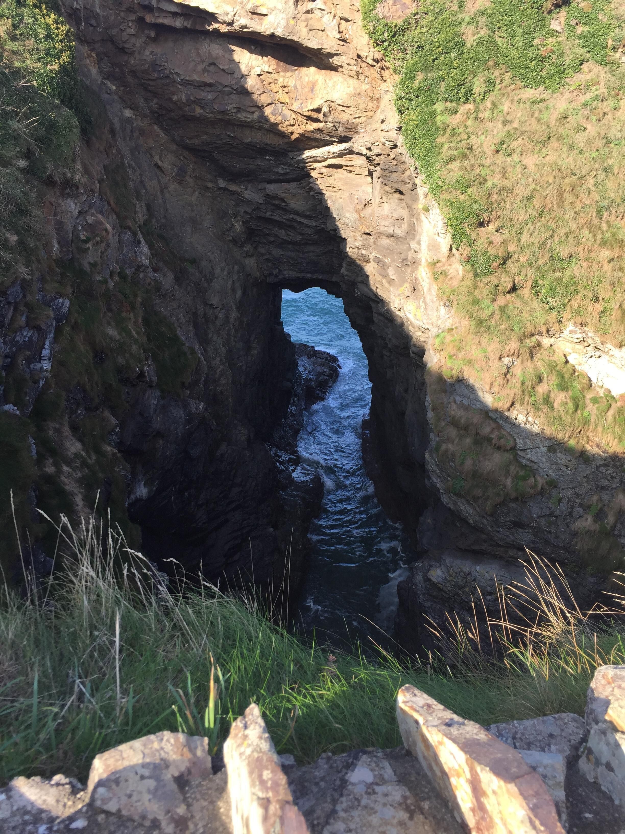 A natural rock formation with a narrow passage leading to a body of water.