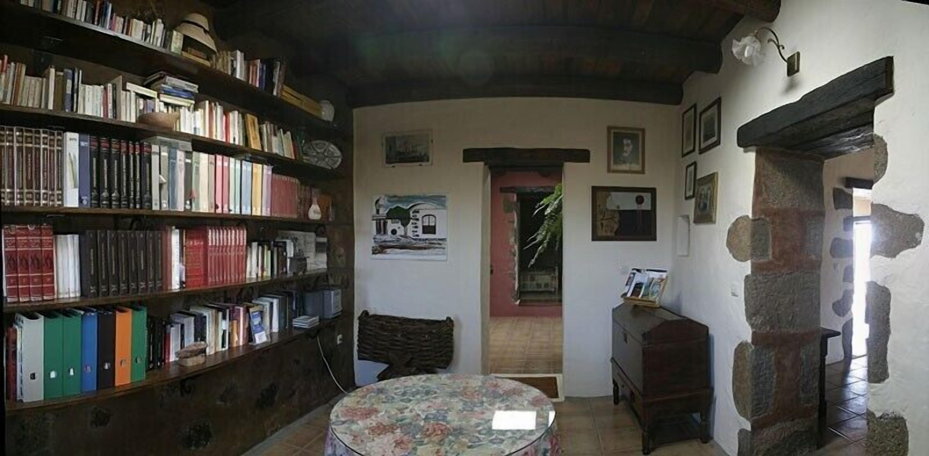 Une bibliothèque chaleureuse avec des étagères, une table ronde et un mur en pierre.