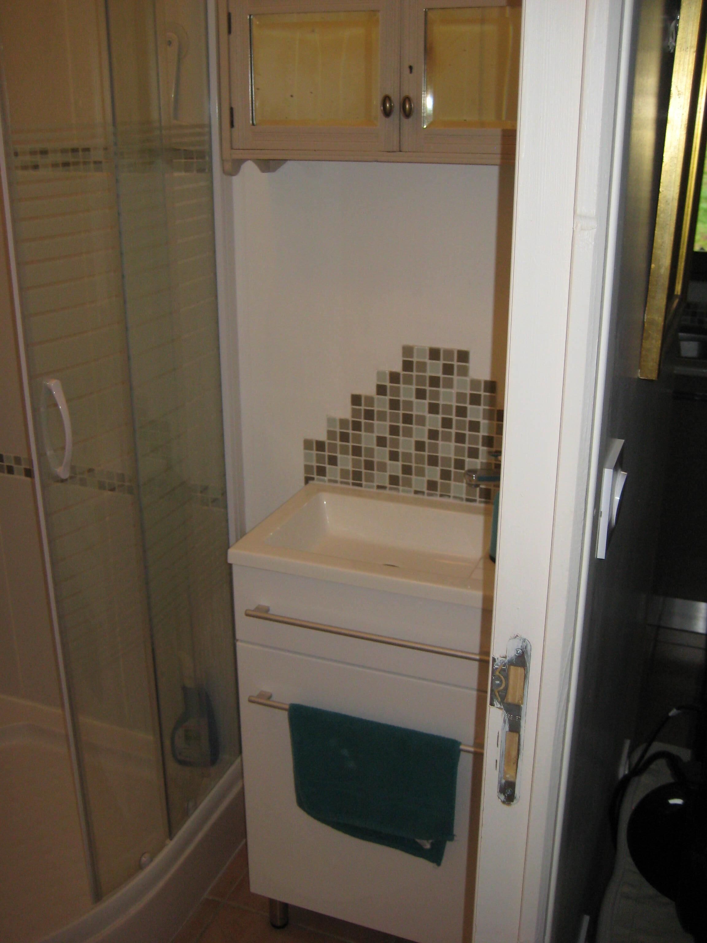 A bathroom with a shower, a sink, and a cabinet.