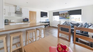 A modern kitchen with white cabinets, a wooden countertop, and a dining area with a table and chairs. There is a sofa and a window with a view of the outside. - Sparkling Clean Fabulous views of Stirling Castle  (Stirling)