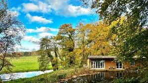 A cabin by a pond with a clear view of the surrounding landscape. - Riverside Lodge New Forest (Godshill)