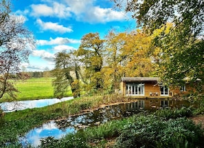 A cabin by a pond with a clear view of the surrounding landscape. - Riverside Lodge New Forest (Godshill)