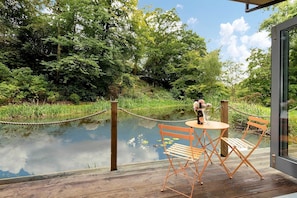 A wooden deck with a table and chairs, a rope barrier, and a bottle of wine.
