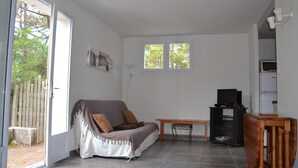 Ein Zimmer mit einer Couch, einem kleinen Tisch, einem Fernseher und einem Kühlschrank.