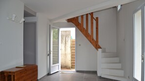 Ein Flur mit einer Holztreppe, einer Schiebeglastür, die nach draußen führt, und einer Holzkommode.