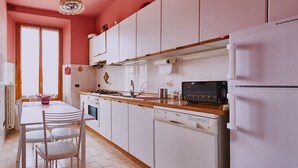 Een keuken met witte kastjes, een houten aanrecht, een magnetron en een koelkast.
