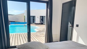 Une chambre avec vue sur une piscine, un lit avec un oreiller et une porte.