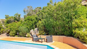 A swimming pool with a tiled deck, surrounded by lush greenery and a stone wall. - Ambra: holiday house with shared pool (Costa Paradiso)