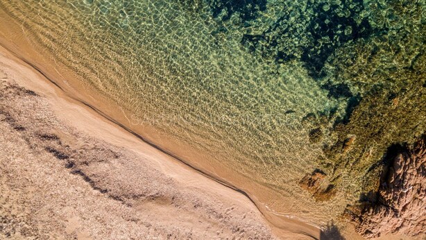 An aerial view of a beach with clear shallow waters, a sandy shore, and rocky outcrops. - Ambra: holiday house with shared pool (Costa Paradiso)
