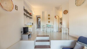 A spacious living area with a staircase leading to a dining area, a television, and a sofa. - Ambra: holiday house with shared pool (Costa Paradiso)