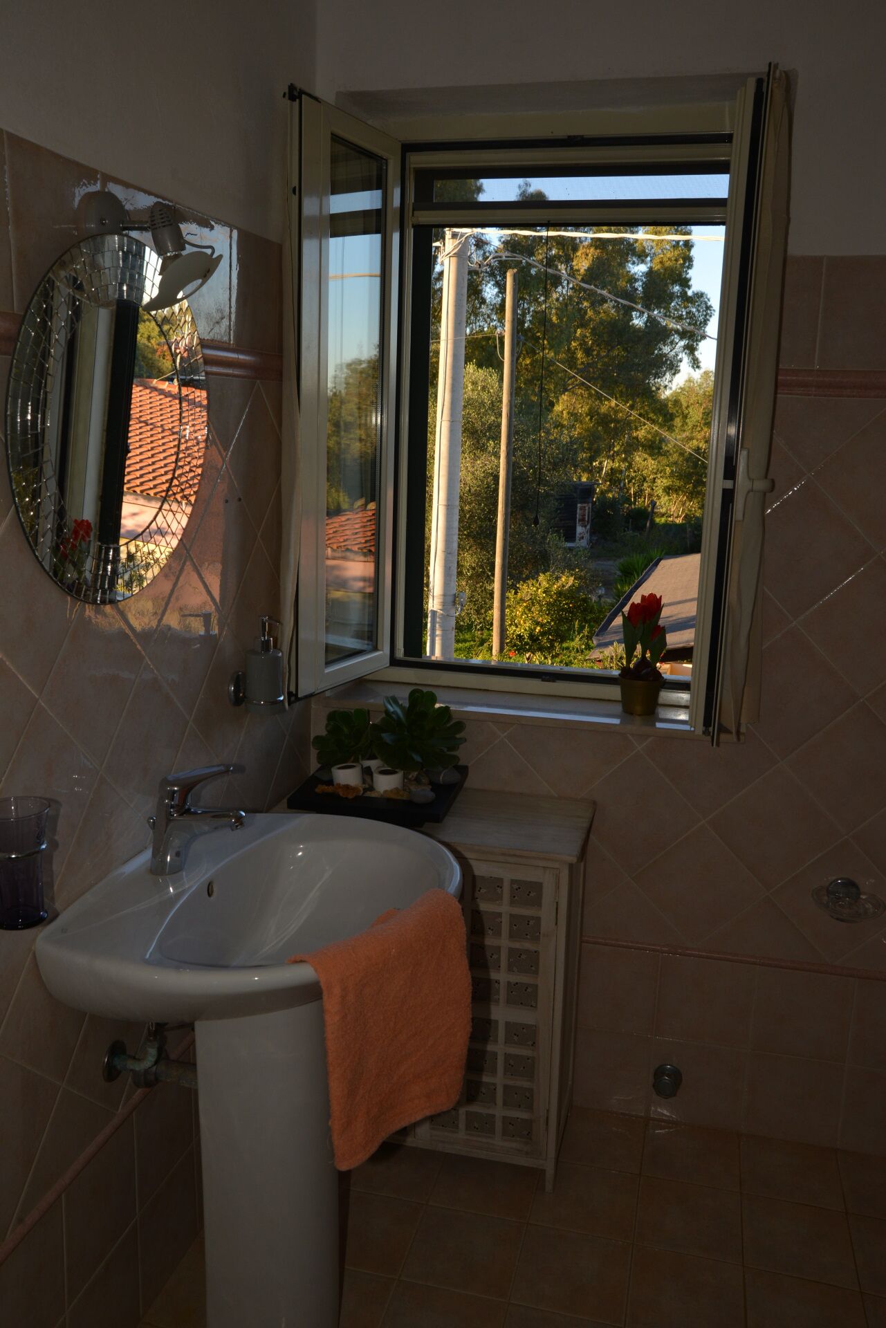 A bathroom with a sink, mirror, and window.