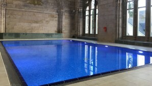 Ein großes Hallenbad mit Steinwänden und Rundbogenfenstern.
