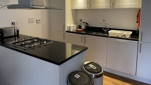 Eine moderne Küche mit Gasherd, Edelstahlgeräten, weißen Schränken und einer schwarzen Arbeitsplatte.