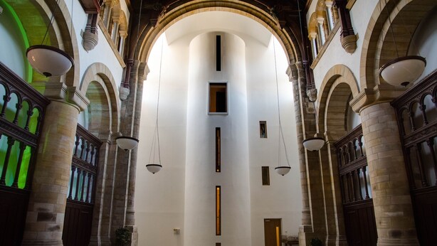 Ein prunkvoller Saal mit hohen Decken, Rundbögen und hängenden Lampen.