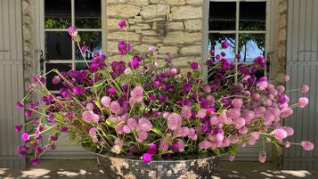 Een grote metalen plantenbak met paarse bloemen op een houten terras.