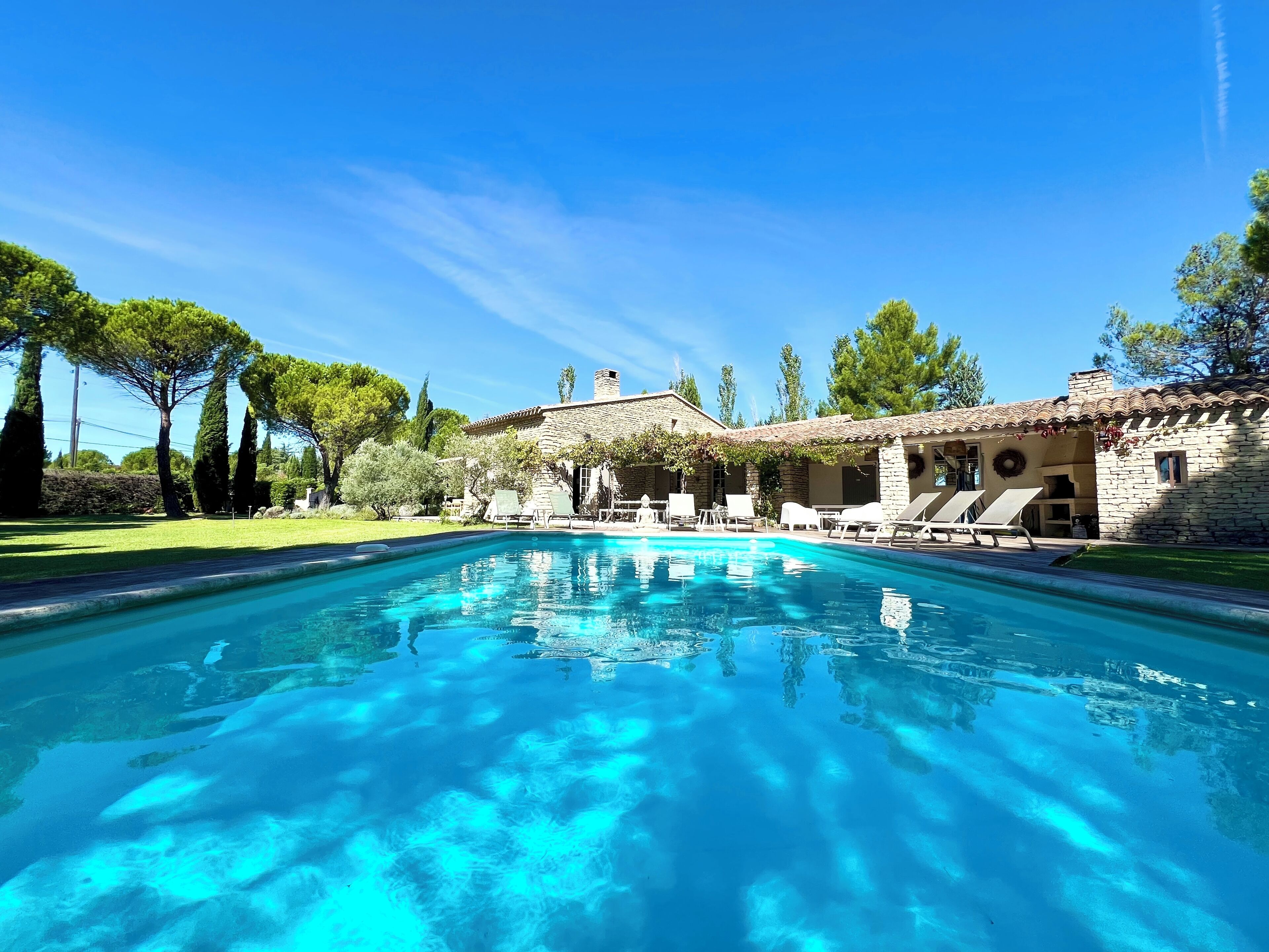 A swimming pool with lounge chairs and a stone building in the background.
