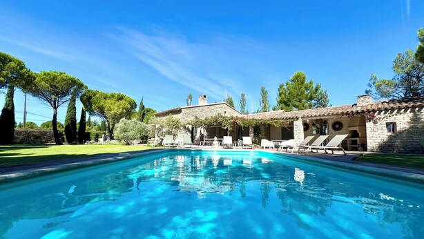 A swimming pool with lounge chairs and a stone building in the background.