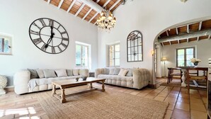 A spacious living room with a large sectional sofa, a wooden coffee table, and a large wall clock.