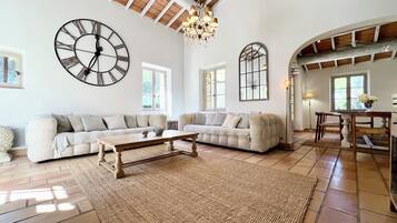 A spacious living room with a large sectional sofa, a wooden coffee table, and a large wall clock.