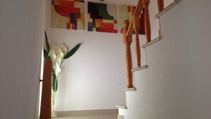 Una scala con ringhiere in legno e un muro bianco decorato con arte astratta colorata.