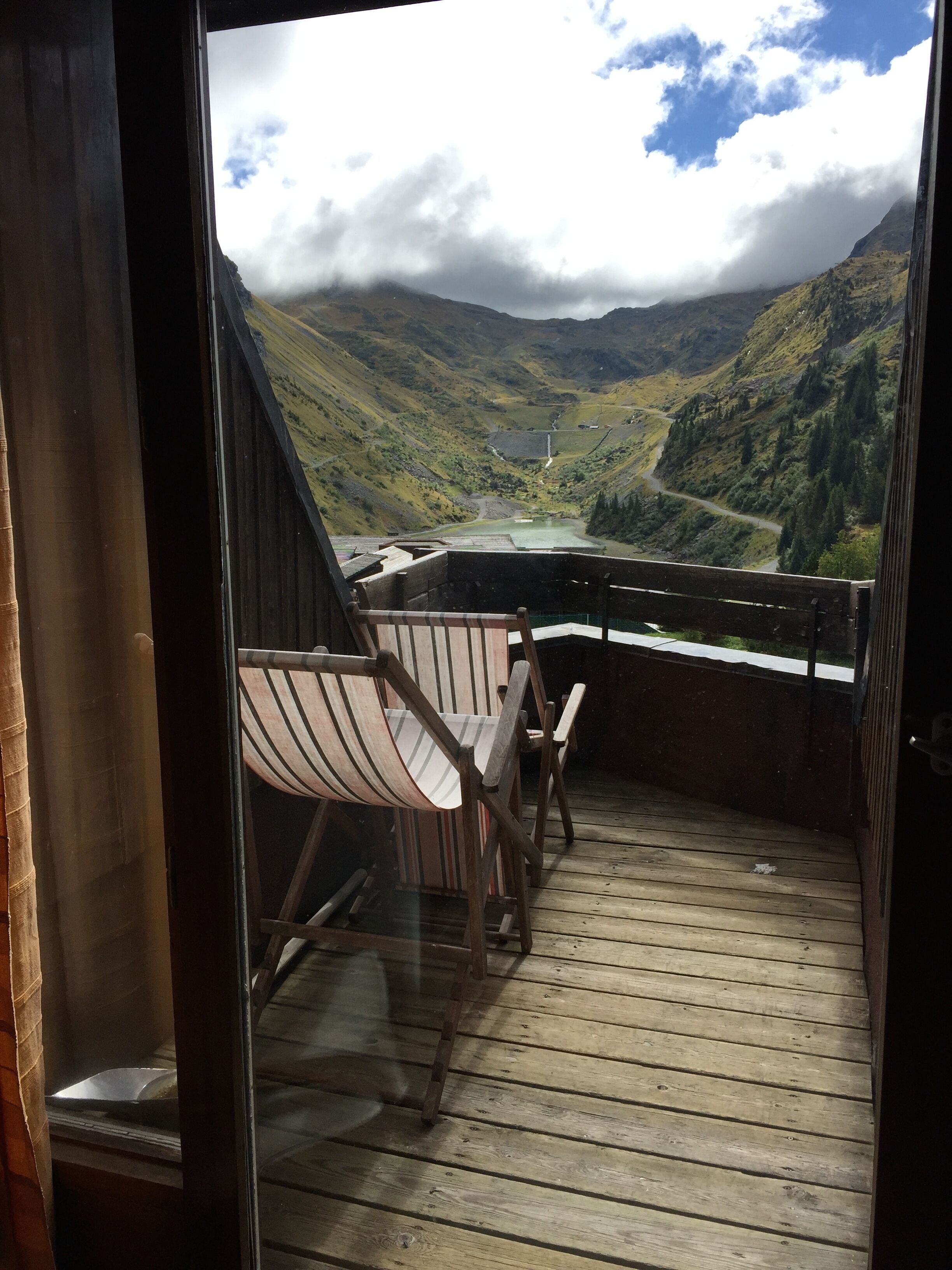 A wooden deck with a view of a valley and mountains.